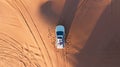 AERIAL. Top view of young couple relaxing on the car's roof at the desert. Royalty Free Stock Photo