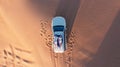 AERIAL. Top view of young couple relaxing on the car's roof at the desert. Royalty Free Stock Photo