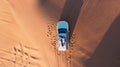 AERIAL. Top view of young couple relaxing on the car's roof at the desert. Royalty Free Stock Photo