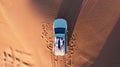 AERIAL. Top view of young couple relaxing on the car's roof at the desert. Royalty Free Stock Photo