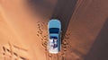 AERIAL. Top view of young couple relaxing on the car's roof at the desert. Royalty Free Stock Photo