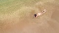 Aerial top view of young woman in bikini relaxing on sand tropical beach by sea and waves from above, girl on tropical island Royalty Free Stock Photo