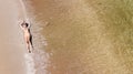 Aerial top view of young woman in bikini relaxing on sand tropical beach by sea and waves from above, girl on tropical island Royalty Free Stock Photo