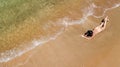 Aerial top view of young woman in bikini relaxing on sand tropical beach by sea and waves from above, girl on island beach Royalty Free Stock Photo