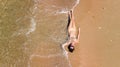 Aerial top view of young woman in bikini relaxing on sand tropical beach by sea and waves from above, girl on island beach Royalty Free Stock Photo
