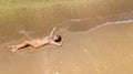 Aerial top view of young woman in bikini relaxing on sand tropical beach by sea and waves from above, girl on tropical island Royalty Free Stock Photo