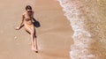 Aerial top view of young woman in bikini relaxing on sand tropical beach by sea and waves from above, girl on tropical island Royalty Free Stock Photo