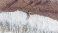 Aerial top view young woman in swimsuit lying on the stone beach, waves touch her legs. Young woman sunbathing and relaxing on the Royalty Free Stock Photo