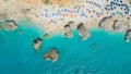 AERIAL: Tourists relaxing on the lounge chairs and swimming in the turquoise sea Royalty Free Stock Photo