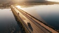 Aerial tracking shot of unknown cars moving along the dam at sea in the evening. Orbetello, Italy