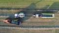 Aerial of tractor baler making straw bales in field after wheat harvest in summer on farm