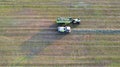 Aerial of tractor baler making straw bales in field after wheat harvest in summer on farm