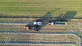 Aerial of tractor baler making straw bales in field after wheat harvest in summer on farm