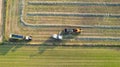 Aerial of tractor baler making straw bales in field after wheat harvest in summer on farm