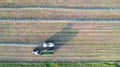 Aerial of tractor baler making straw bales in field after wheat harvest in summer on farm