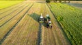 Aerial of tractor baler making straw bales in field after wheat harvest in summer on farm