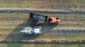 Aerial of tractor baler making straw bales in field after wheat harvest in summer on farm