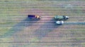 Aerial of tractor baler making straw bales in field after wheat harvest in summer on farm