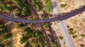 Aerial of train tracks crossing over tracks and road in desert Royalty Free Stock Photo