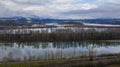 Aerial of trees reflecting in river, railroad runs along