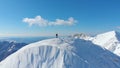 AERIAL: Unknown skier hikes up to the top of the snowy mountain in the Alps. Royalty Free Stock Photo