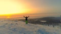 AERIAL: Unrecognizable female skier looks over the spectacular Lapland at sunset