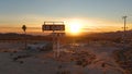 AERIAL: Unrecognizable photographer explores abandoned fuel station at sunset. Royalty Free Stock Photo