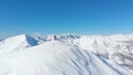 AERIAL: Unrecognizable skier reaches the summit of a snowy mountain in the Alps.