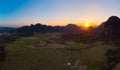 Aerial: Vang Vieng backpacker travel destination in Laos, Asia. Sunset over scenic cliffs and rock pinnacles, rice paddies valley