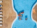 Aerial vertical view of group of women friends have fun together in summer holiday vacation at pool resort with coloured