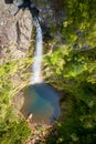 Aerial, vertical view of Risco waterfall, falling to lake on the bottom of steep canyon covered in green vegetation.