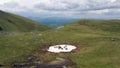 Aerial video of Herd of horses hides from horseflies on a snowfield. Kurai mountain range. Group of tourists on background