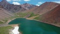 Aerial video of Mountain Spirits Lake in Altai mountains. Herd of horses hides from horseflies on a snowfield