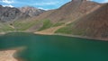 Aerial video of Mountain Spirits Lake in Altai mountains. Herd of horses hides from horseflies on a snowfield