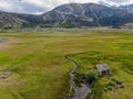 Aerial view of abandoned little small wooden house in the green valley of a mountain