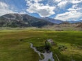 Aerial view of abandoned little small wooden house in the green valley of a mountain