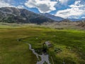 Aerial view of abandoned little small wooden house in the green valley of a mountain