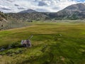 Aerial view of abandoned little small wooden house in the green valley of a mountain