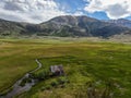 Aerial view of abandoned little small wooden house in the green valley of a mountain