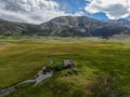 Aerial view of abandoned little small wooden house in the green valley of a mountain