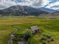 Aerial view of abandoned little small wooden house in the green valley of a mountain