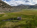 Aerial view of abandoned little small wooden house in the green valley of a mountain