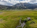 Aerial view of abandoned little small wooden house in the green valley of a mountain