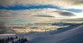 Aerial view above the clouds at mountain peaks covered with snow, lighting by the sun Royalty Free Stock Photo