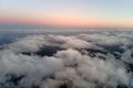 Aerial view from above at high altitude of dense puffy cumulus clouds flying in evening. Amazing sunset from airplane Royalty Free Stock Photo