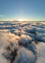 Aerial view from above at high altitude of dense puffy cumulus clouds flying in evening. Amazing sunset from airplane Royalty Free Stock Photo