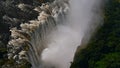 Aerial view in abysm of Victoria Falls and rainforest with enormous water spray at the end of rainy season from helicopter. Royalty Free Stock Photo