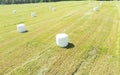 Aerial view agricultural landscape. Straw packages on field. Flying over cereal bale of hay wrapped in plastic white foil.