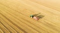 Aerial view of agricultural tractor with cargo cart in field. Beautiful sunset.