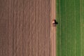 Aerial view of agricultural tractor with tiller attached driving on dirt road